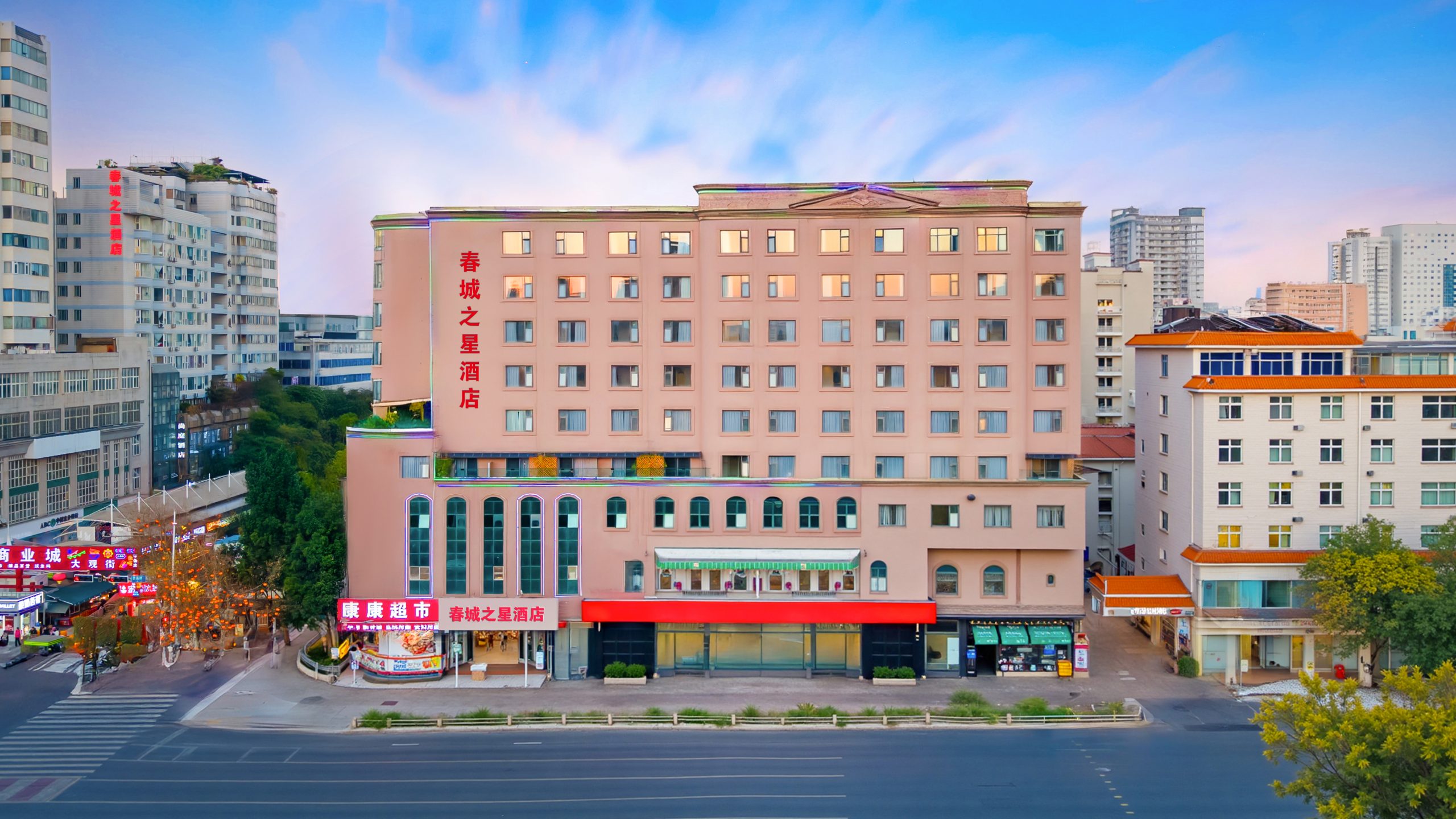 春城之星精品酒店正面全景，粉色建筑外观、底层商铺与酒店入口一目了然。