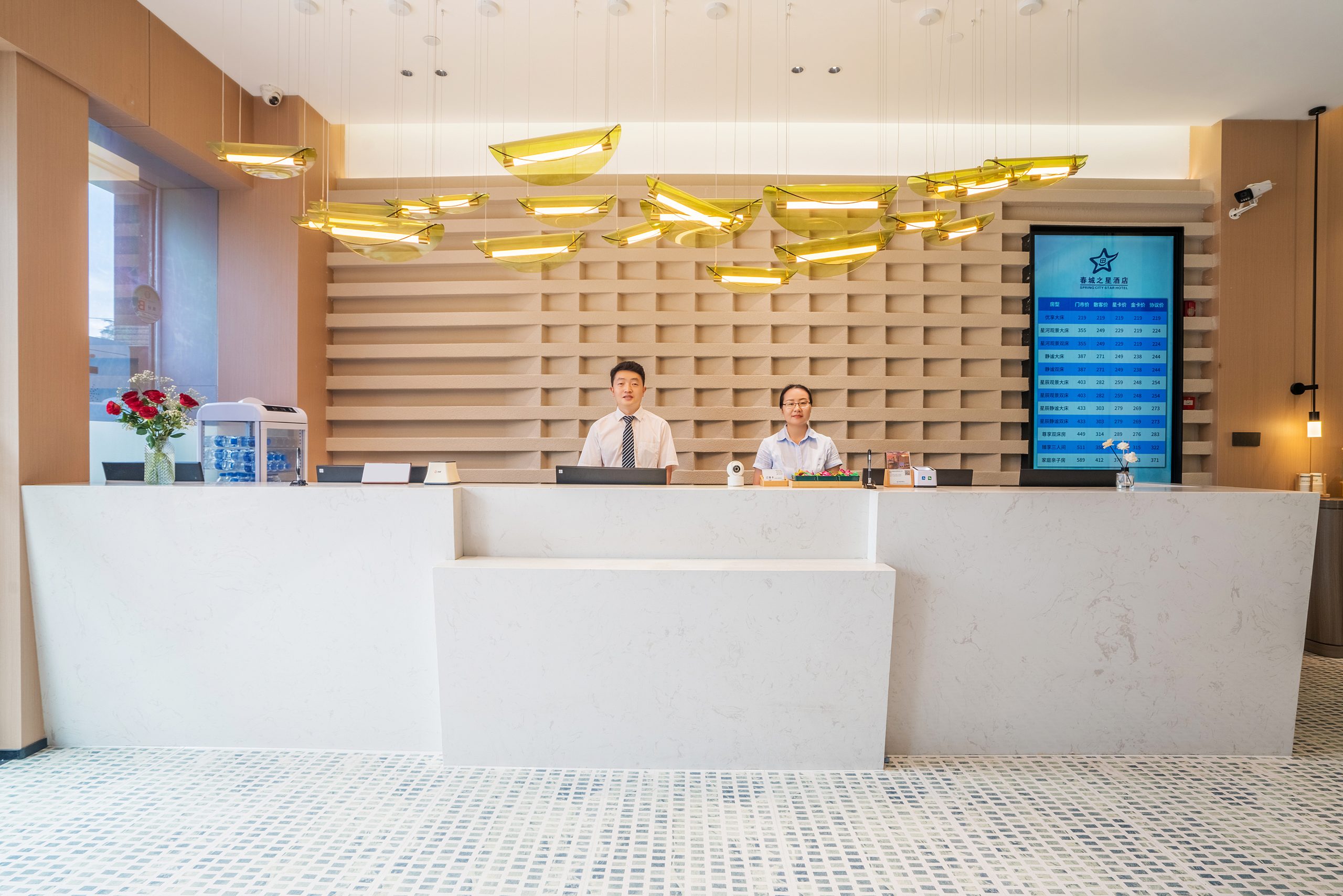 Reception desk at Spring City Star Boutique Hotel with staff, digital rate display, and designer chandeliers.